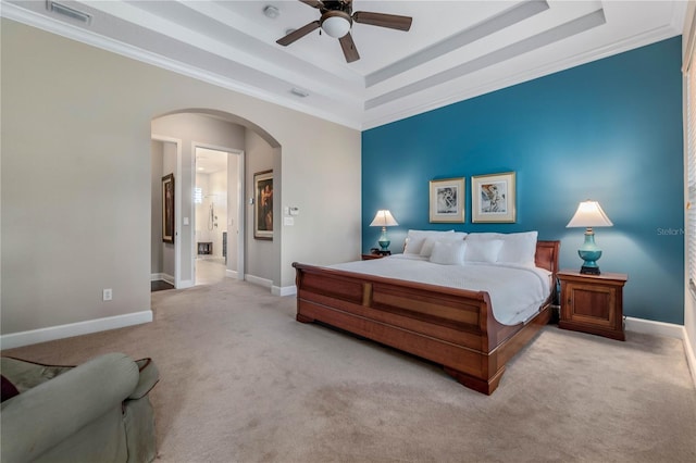 bedroom with light carpet, visible vents, a tray ceiling, and arched walkways