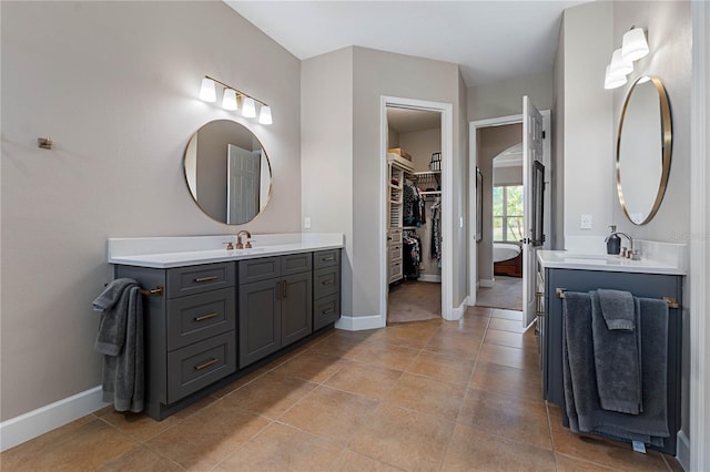 full bath featuring two vanities, a sink, and baseboards