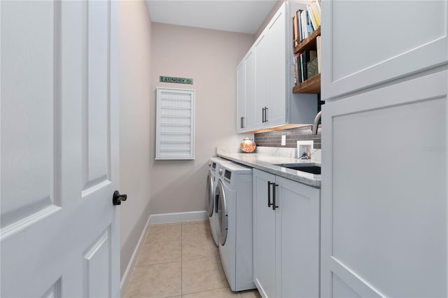 washroom featuring light tile patterned floors, a sink, baseboards, independent washer and dryer, and cabinet space