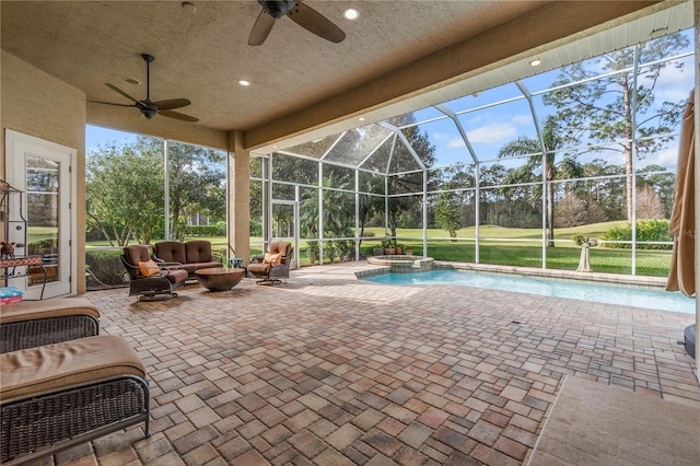 view of pool featuring a patio, a pool with connected hot tub, a ceiling fan, glass enclosure, and an outdoor living space