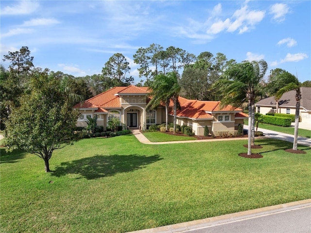 mediterranean / spanish house with a tile roof, a front lawn, and stucco siding