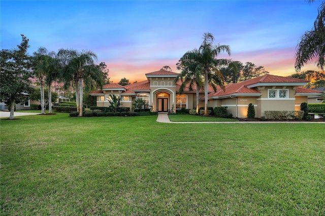 mediterranean / spanish-style house with a front lawn, a tile roof, and stucco siding