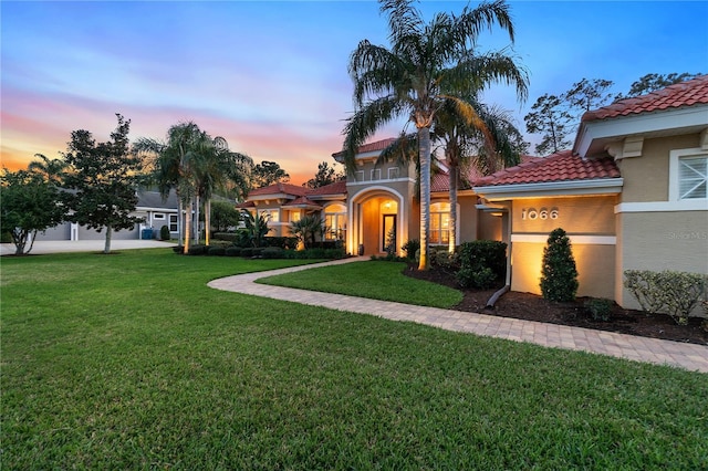 mediterranean / spanish-style house featuring stucco siding, a tiled roof, and a yard