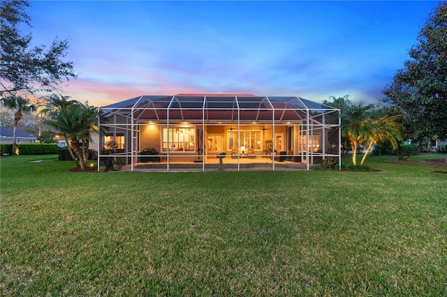 rear view of property with glass enclosure and a yard