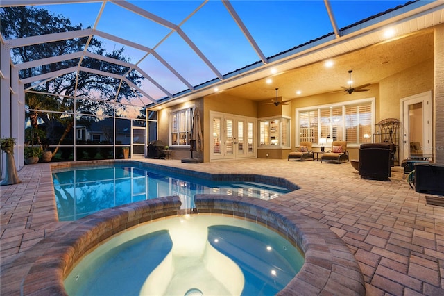 pool at dusk with glass enclosure, ceiling fan, a patio, and an outdoor hangout area