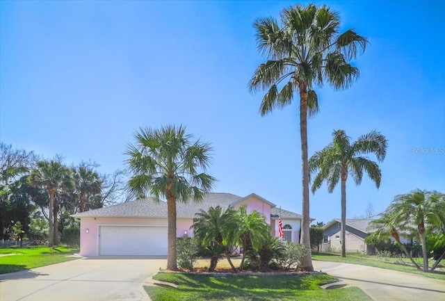 view of front of home with an attached garage, a front lawn, concrete driveway, and stucco siding