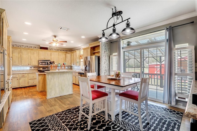 kitchen with stainless steel appliances, visible vents, light brown cabinetry, light wood-style floors, and a kitchen island