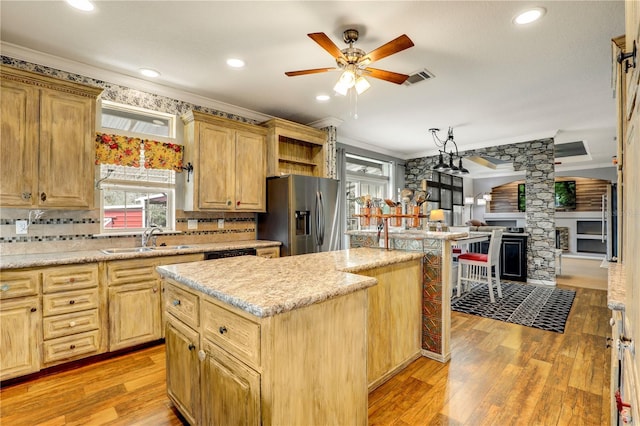 kitchen featuring stainless steel fridge, light wood-style flooring, a kitchen island, crown molding, and a sink