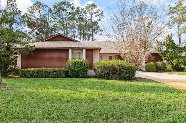 single story home featuring driveway, roof with shingles, and a front yard