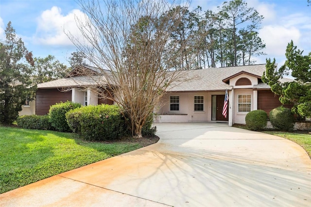 single story home featuring driveway, a front lawn, a shingled roof, and stucco siding