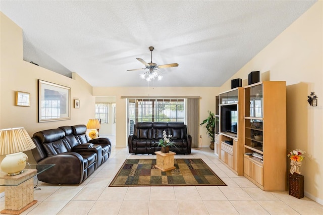 living room with lofted ceiling, a textured ceiling, light tile patterned flooring, and a ceiling fan
