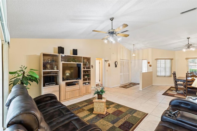 living room featuring visible vents, a ceiling fan, lofted ceiling, a textured ceiling, and light tile patterned flooring