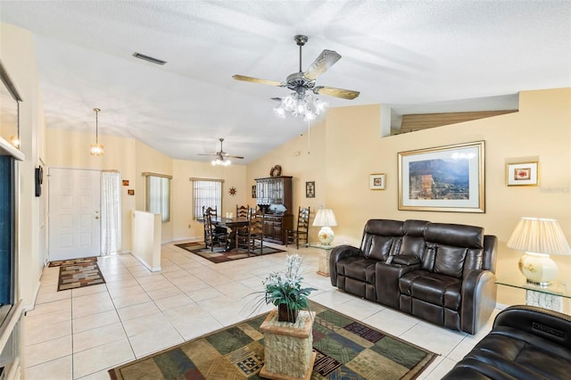 living area with light tile patterned floors, a textured ceiling, visible vents, baseboards, and vaulted ceiling