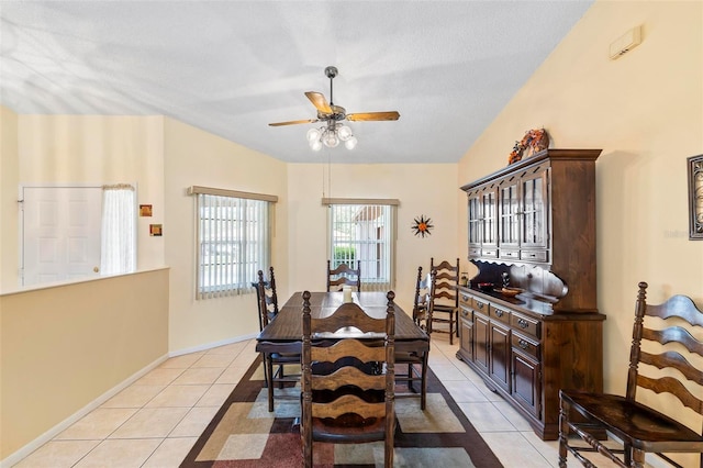 dining room featuring light tile patterned floors, baseboards, lofted ceiling, ceiling fan, and a textured ceiling