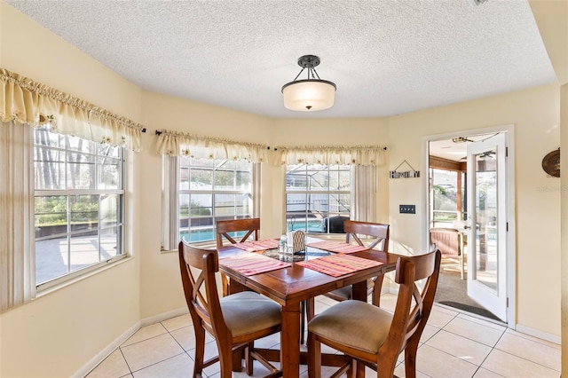 dining room with a textured ceiling, light tile patterned flooring, and baseboards
