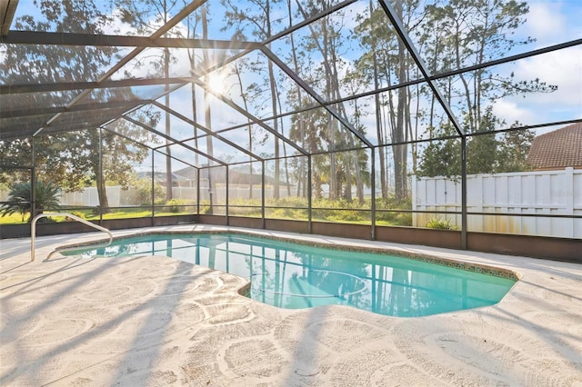 pool featuring glass enclosure, fence, and a patio