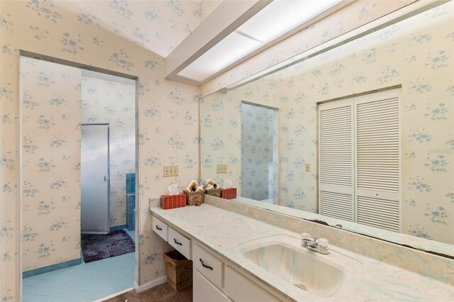 bathroom with vanity, baseboards, and wallpapered walls