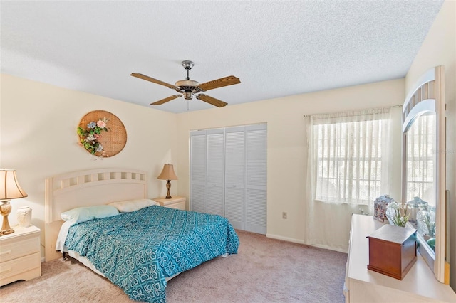 bedroom with a closet, carpet flooring, ceiling fan, and a textured ceiling