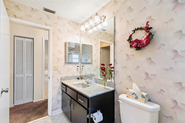 bathroom featuring wallpapered walls, visible vents, toilet, a textured ceiling, and a closet