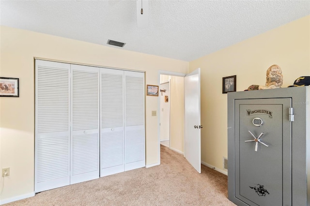 unfurnished bedroom featuring light carpet, baseboards, visible vents, a textured ceiling, and a closet