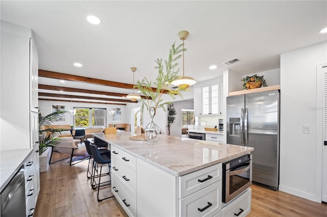 kitchen with light stone counters, stainless steel appliances, hanging light fixtures, white cabinetry, and a kitchen island