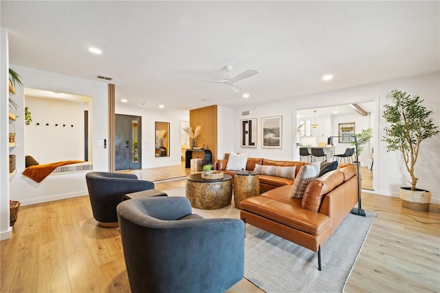 living room featuring baseboards, light wood finished floors, a ceiling fan, and recessed lighting