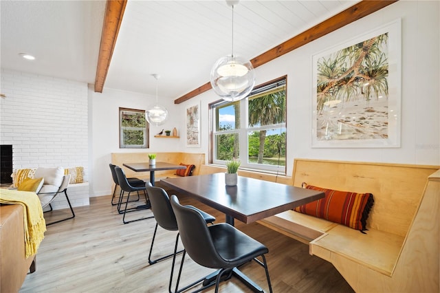 dining area with light wood-style floors, breakfast area, and beamed ceiling