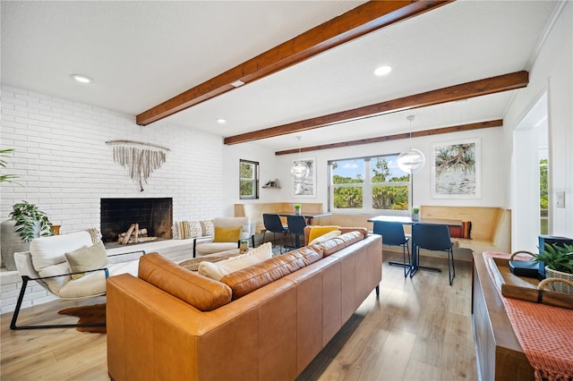 living room featuring beamed ceiling, a fireplace, light wood-style flooring, and recessed lighting