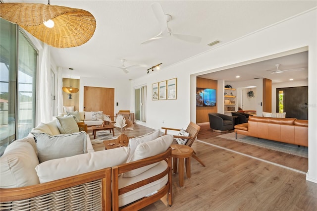 living room with a ceiling fan, visible vents, and wood finished floors