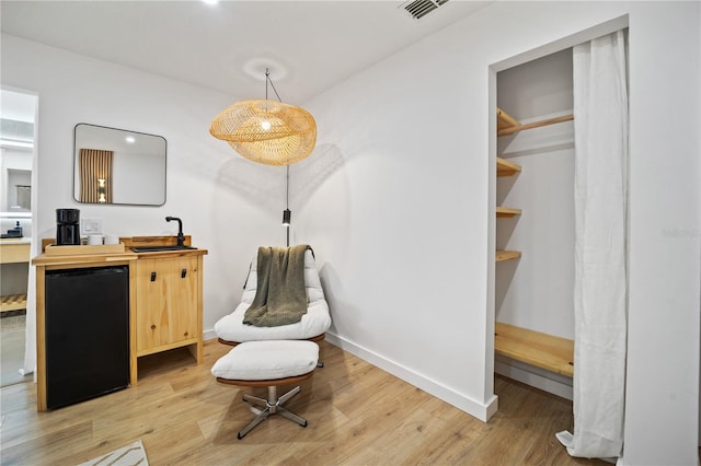 living area featuring light wood finished floors, baseboards, and visible vents