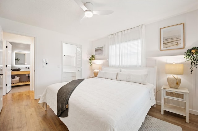 bedroom with a ceiling fan, connected bathroom, baseboards, and wood finished floors