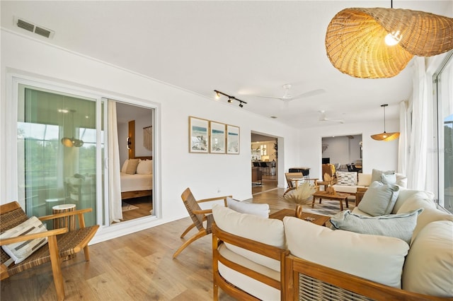 living area with ceiling fan, light wood finished floors, and visible vents