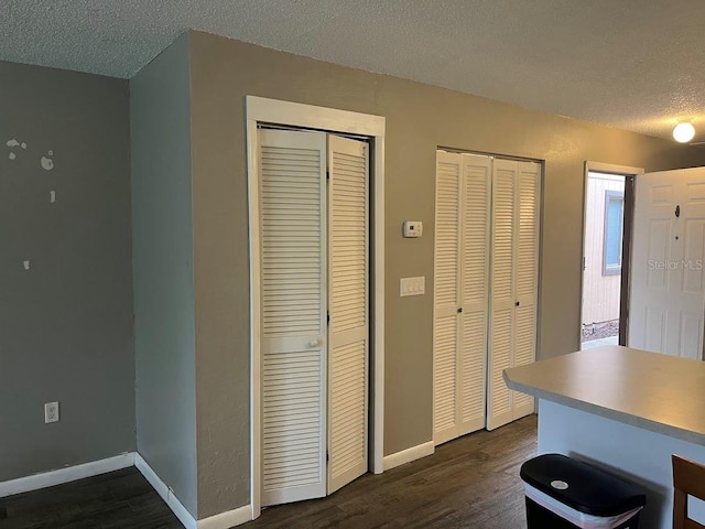 interior space with a textured ceiling, dark wood finished floors, and baseboards