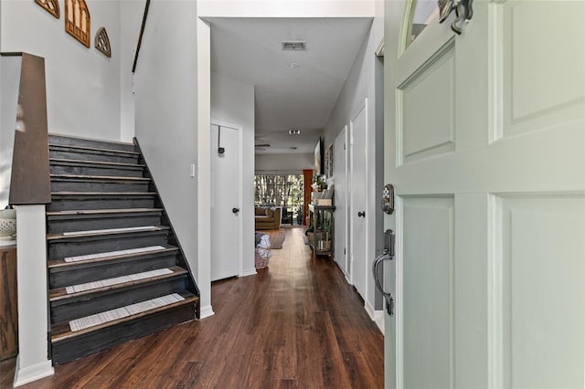 entrance foyer with stairway, dark wood finished floors, visible vents, and baseboards