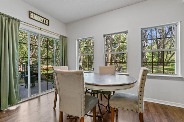 dining area featuring a textured ceiling, baseboards, and wood finished floors