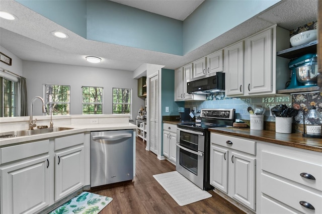 kitchen featuring tasteful backsplash, white cabinets, dark wood finished floors, stainless steel appliances, and a sink