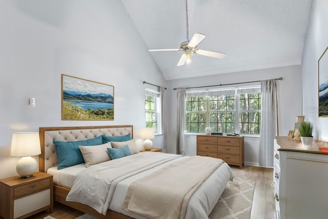 bedroom with light wood-type flooring, ceiling fan, high vaulted ceiling, and a textured ceiling