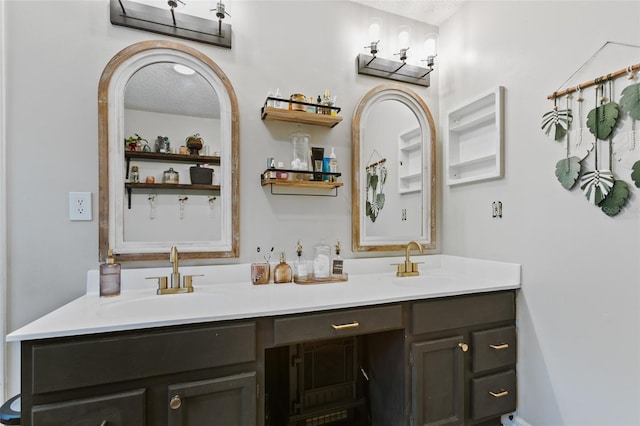 full bathroom featuring a sink, a textured ceiling, and double vanity