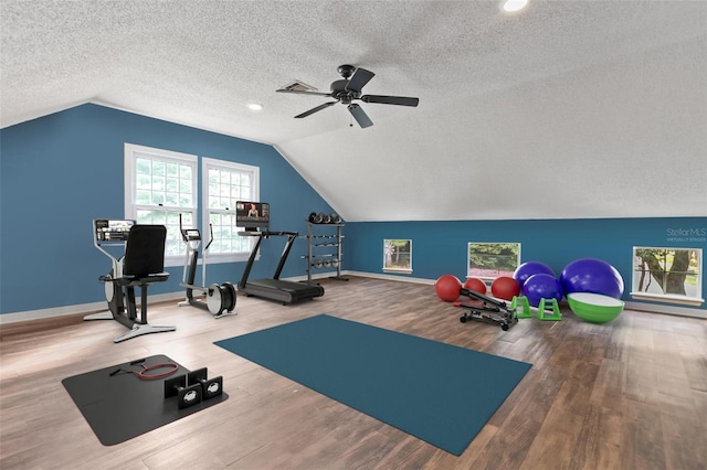 workout area featuring lofted ceiling, ceiling fan, a textured ceiling, wood finished floors, and baseboards