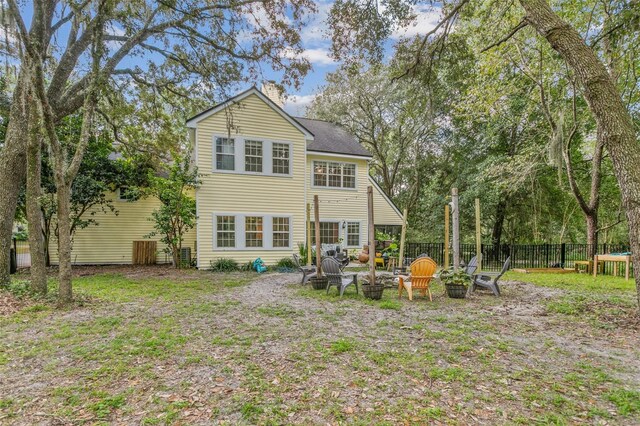 back of house featuring an outdoor fire pit, a chimney, and fence