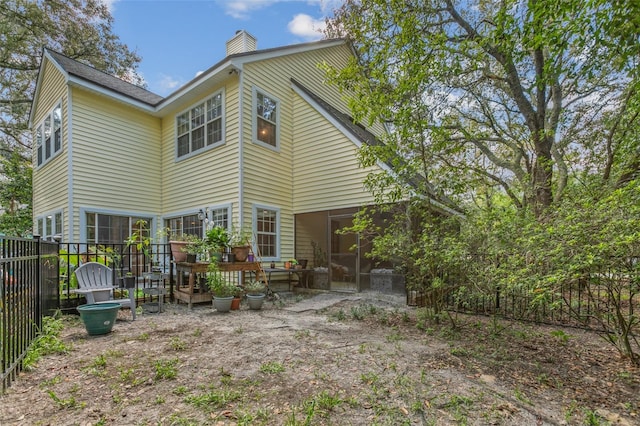 back of house with a chimney and fence