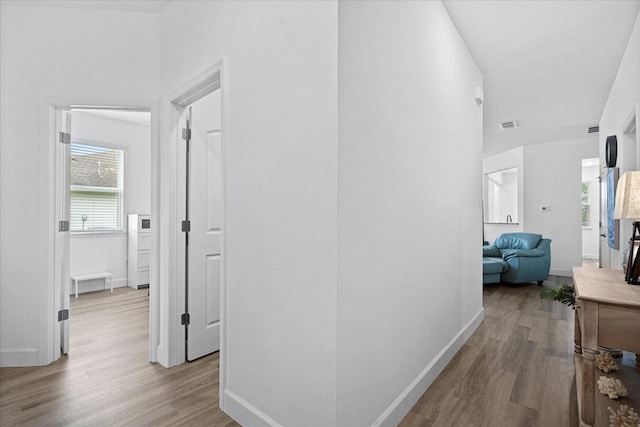 hall with visible vents, baseboards, and wood finished floors