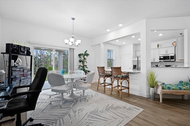 dining area featuring an inviting chandelier, baseboards, wood finished floors, and recessed lighting