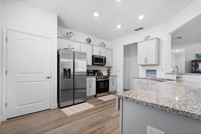 kitchen featuring stainless steel appliances, light wood-type flooring, visible vents, and a sink