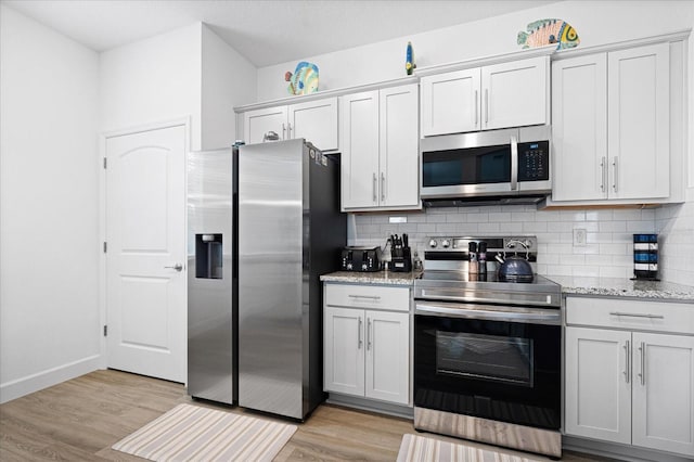 kitchen featuring baseboards, decorative backsplash, light stone counters, stainless steel appliances, and light wood-type flooring