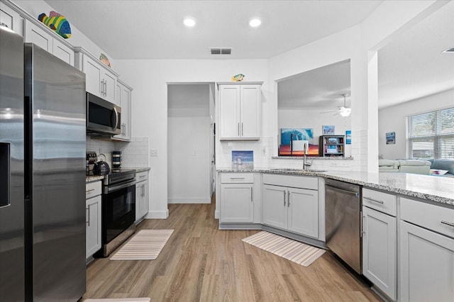 kitchen featuring light wood finished floors, visible vents, appliances with stainless steel finishes, a ceiling fan, and a sink