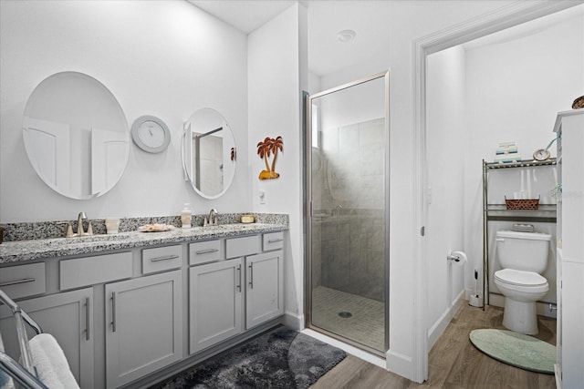 bathroom with double vanity, wood finished floors, a stall shower, and a sink