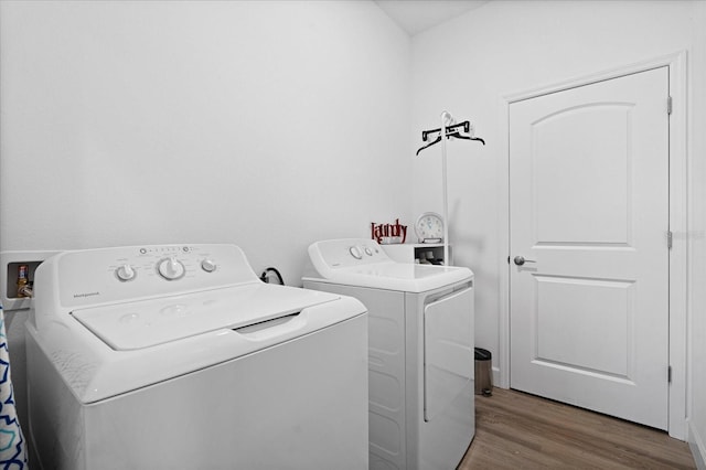 laundry area with laundry area, wood finished floors, and washing machine and dryer