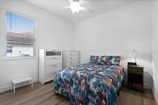 bedroom with wood finished floors, a ceiling fan, and baseboards