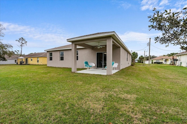 rear view of property featuring a ceiling fan, a yard, a patio, and stucco siding